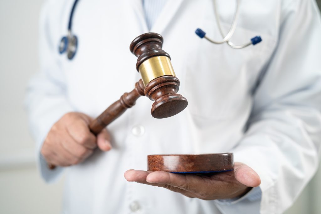 Doctor holding judge gavel, forensic medicine, medical law and crime justice concept.