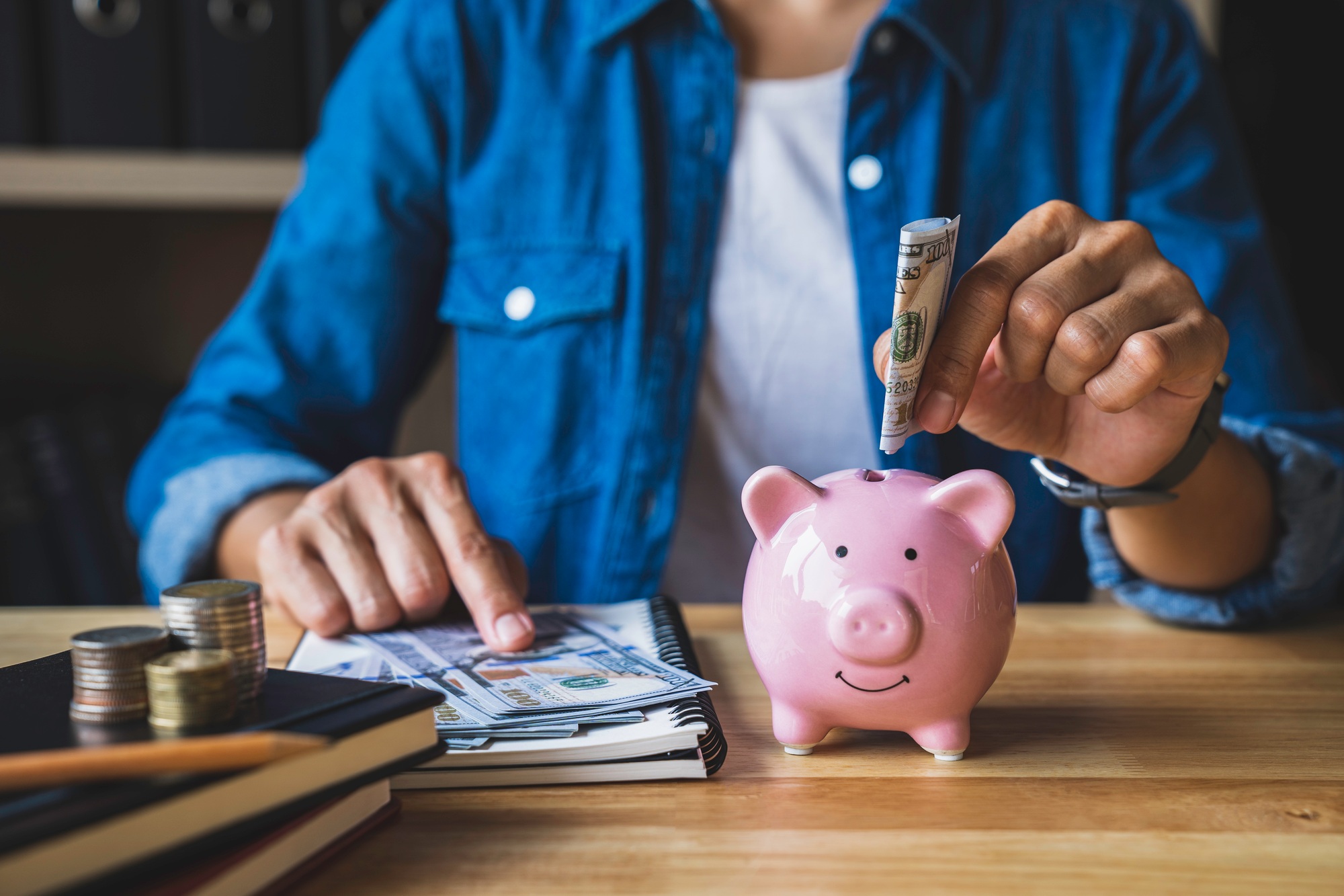 Woman folds dollar bills into pig piggy bank to save money for the future. after retirement and reco